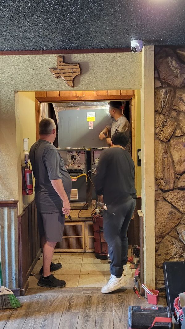 HVAC technicians working on heating system in attic